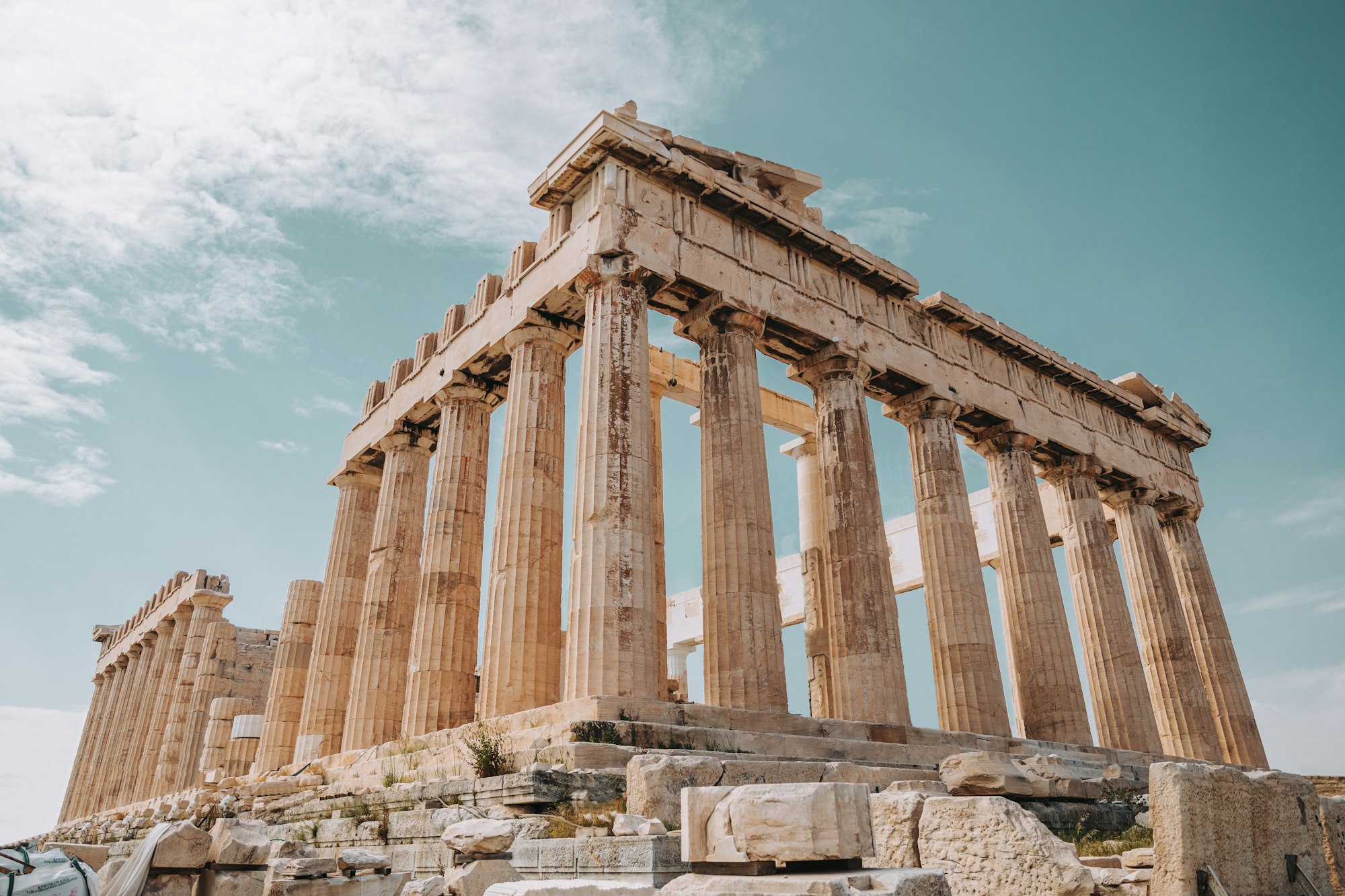 The Parthenon on the Acropolis seen from below, against a pale sky.